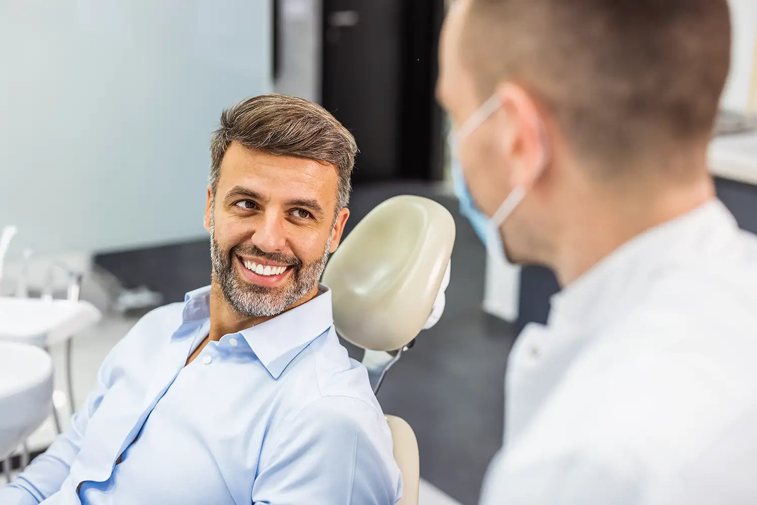 older man in a dentist chair speaking with an oral surgeon